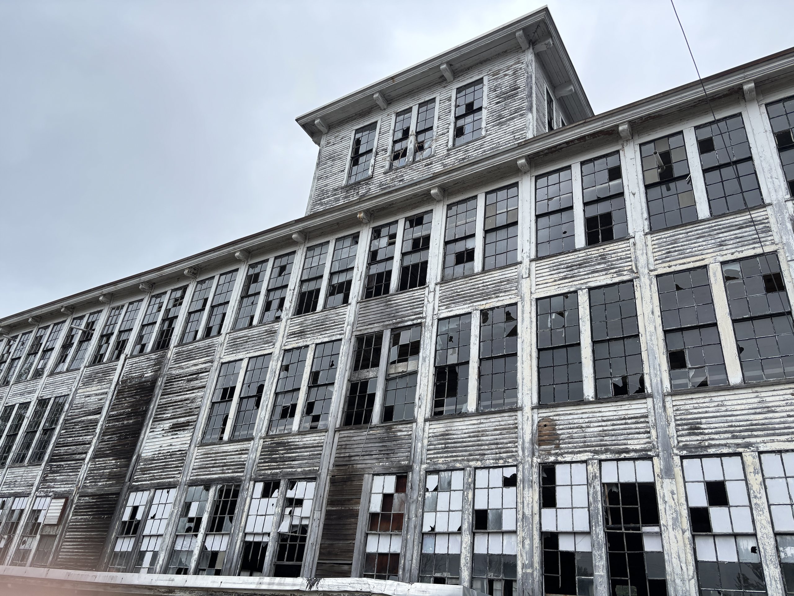 Close view of the weathered timber and tall broken windows of an old New England mill