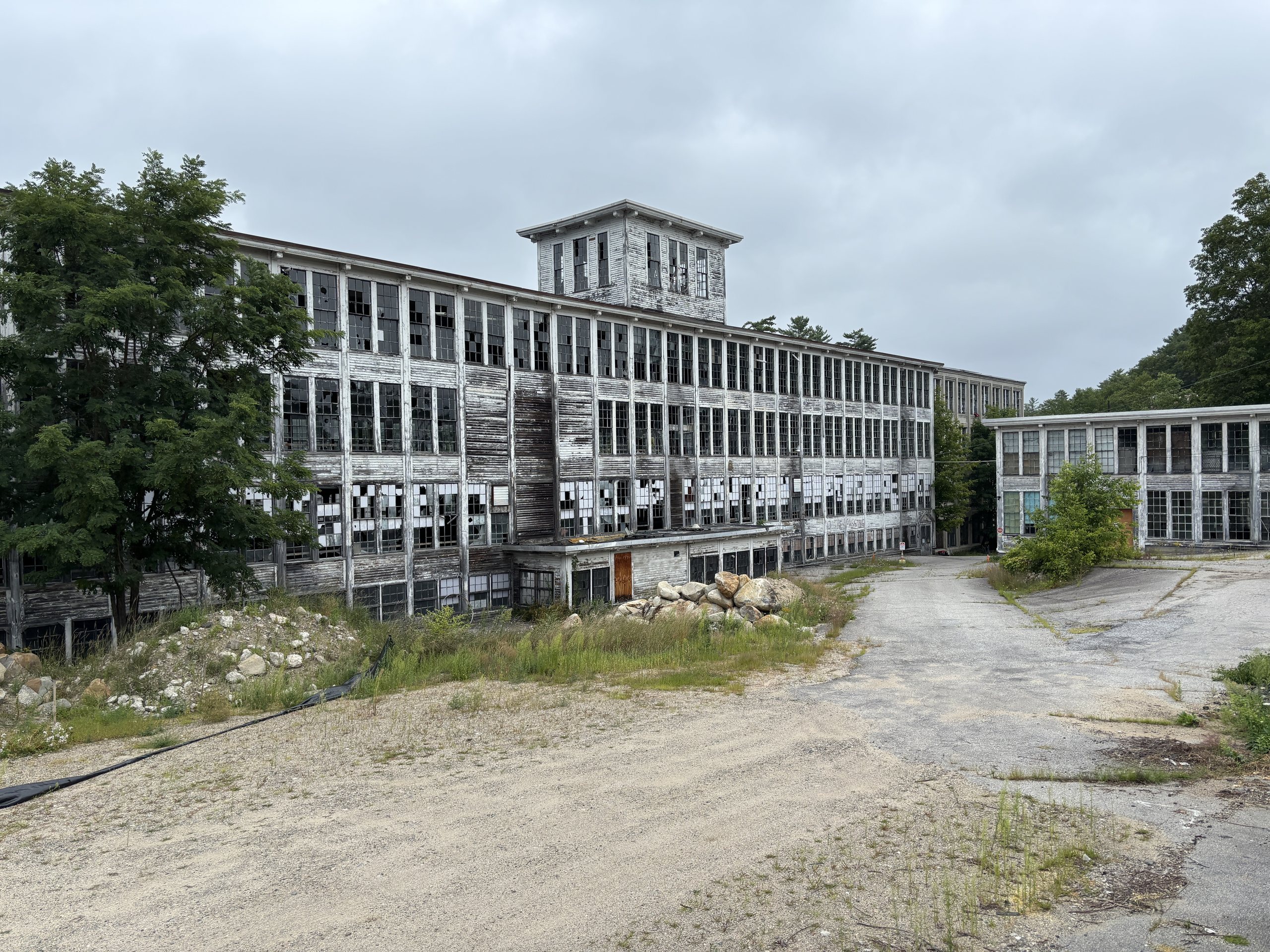 A weathered New England mill complex and its open grounds